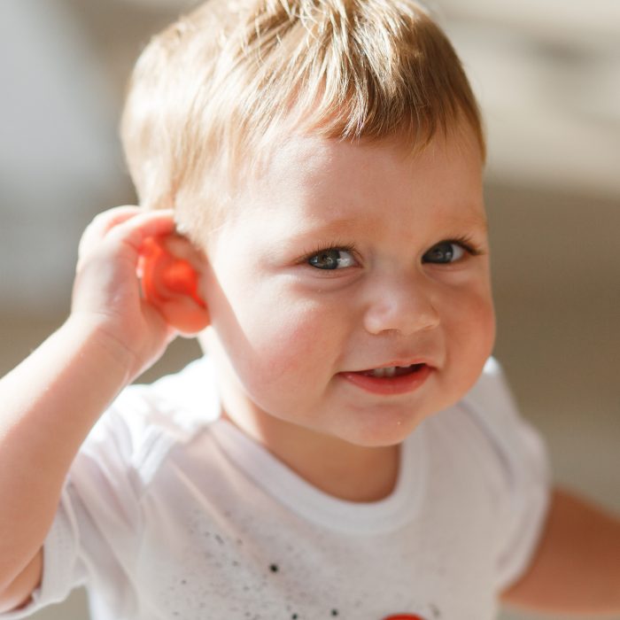 baby boy listens put hand his ear